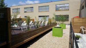 A patio with chairs and a green planter.