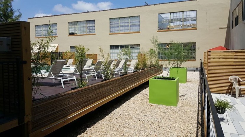A patio with chairs and a green planter.