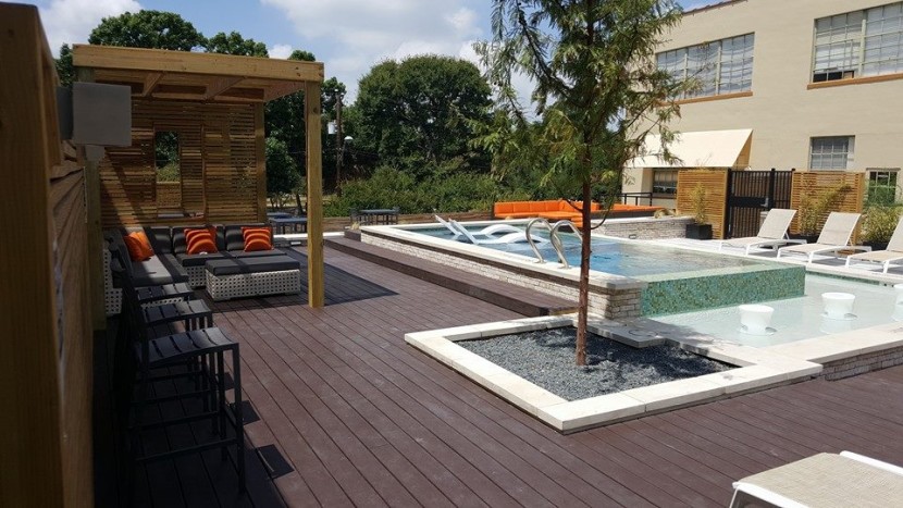 A swimming pool and lounge chairs on a rooftop deck.